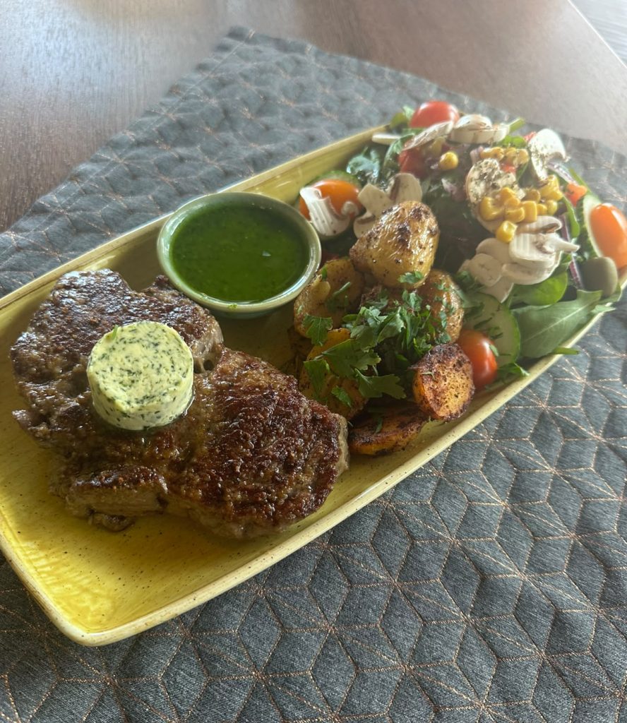 Entrecôte mit Kräuterbutter, Bratkartoffeln, Kräutersoße und gemischtem Salat