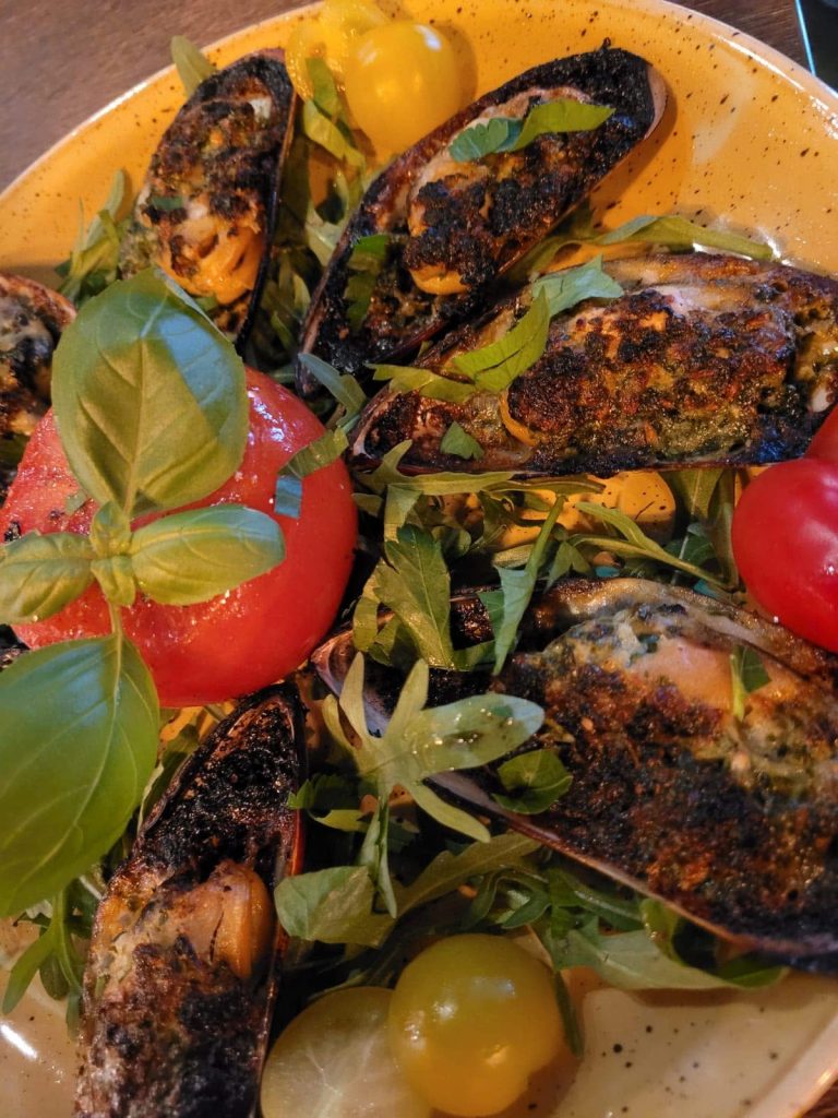 Gratinierte Muscheln mit Kräuterkruste auf Rucola und Tomaten