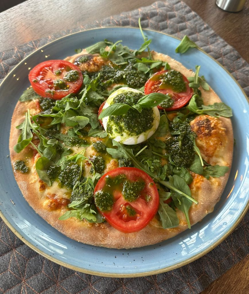 Pizza mit Burrata, frischen Tomaten, Rucola und Pesto