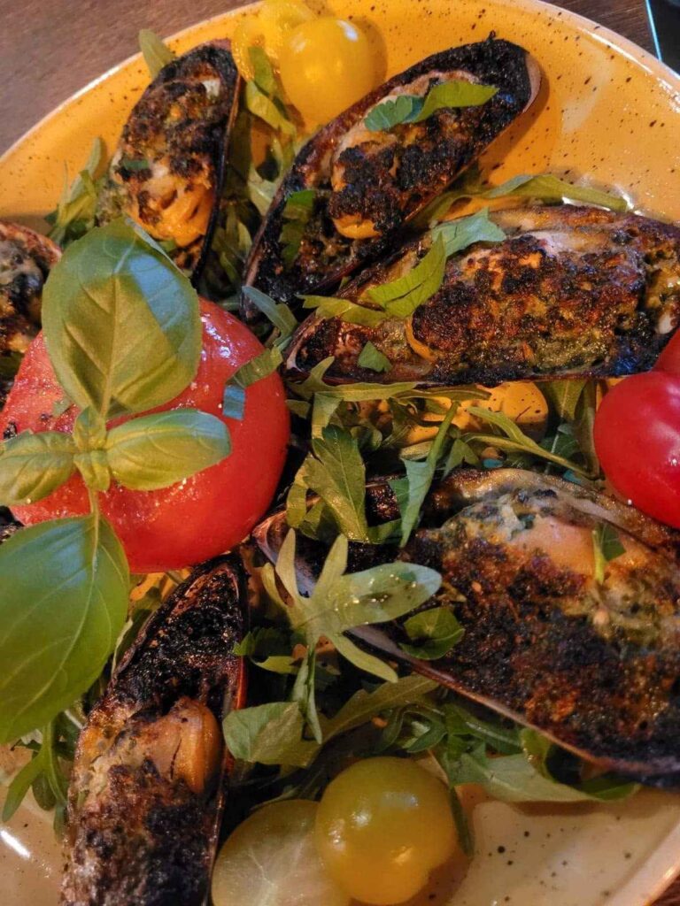 Gratinierte Muscheln mit Kräuterkruste auf Rucola und Tomaten