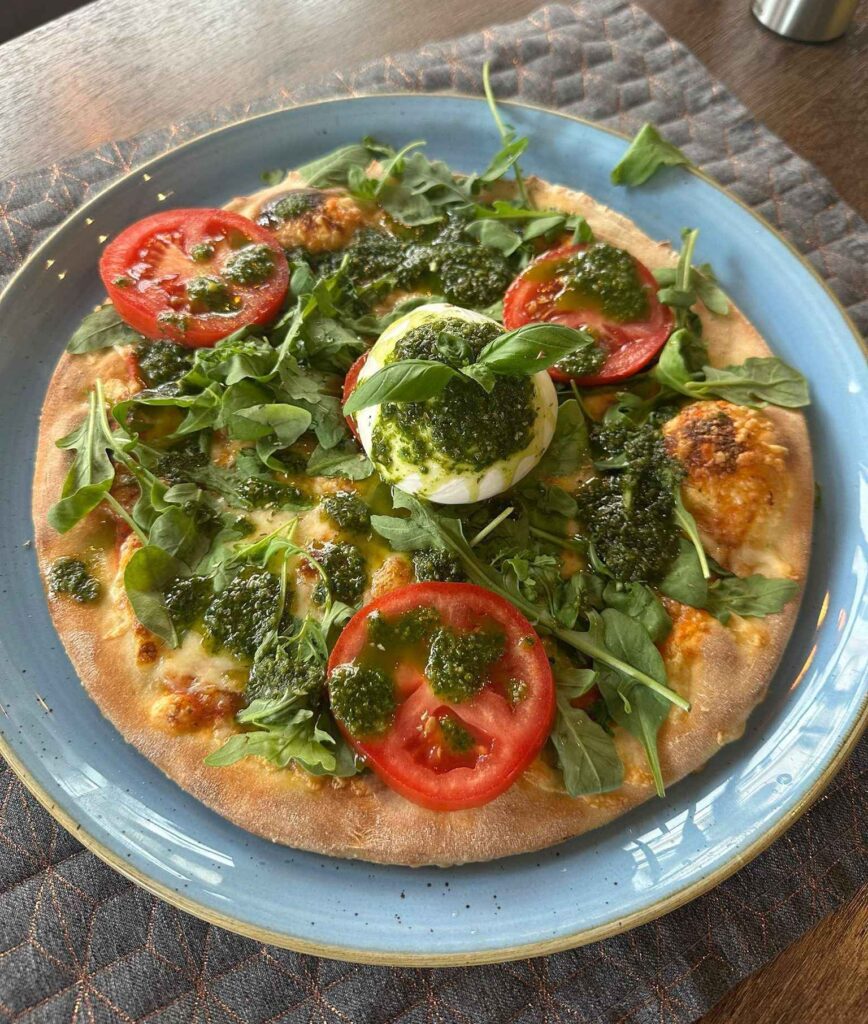 Pizza mit Burrata, frischen Tomaten, Rucola und Pesto